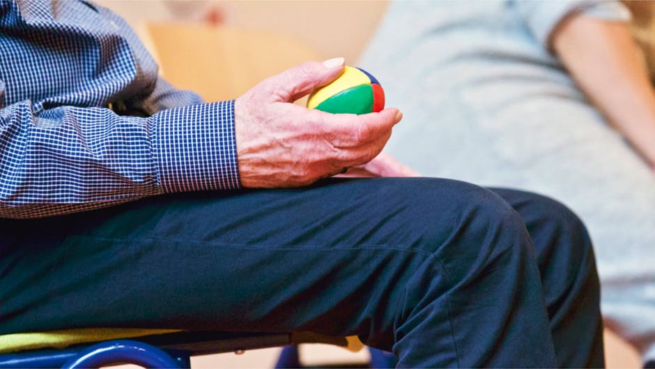 Elderly patient using therapy ball for fine motor rehabilitation